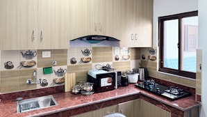Een keuken met houten kastjes, een magnetron, een koffiezetapparaat en een raam met uitzicht.