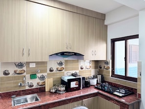 Una cocina con armarios de madera, microondas, cafetera y ventana con vistas.