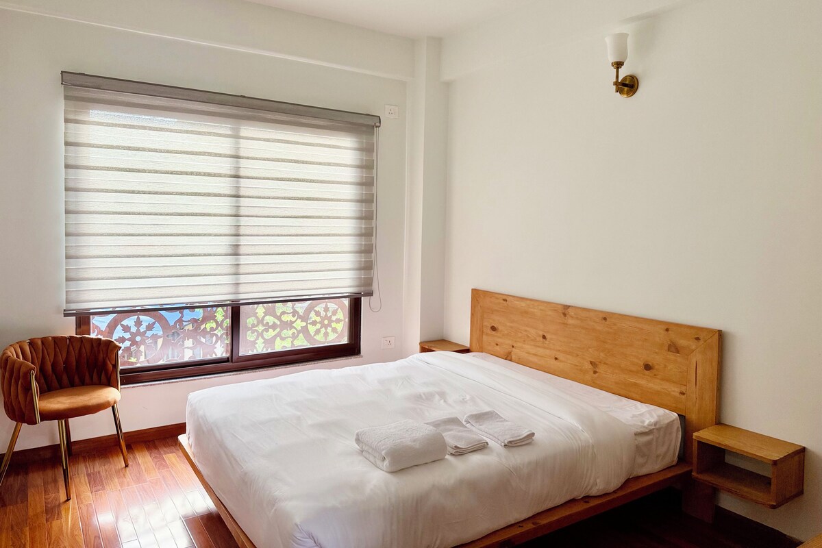 Una camera da letto con un letto, una sedia, un comodino e una finestra con persiane.
