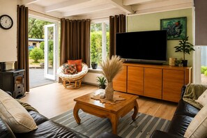 Una sala de estar con un sofá, una mesa de centro, un televisor y una ventana con cortinas.