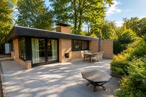 A modern house with a patio, a dining table, and a fireplace. - Zenda's natuurhuisje (Lanaken)
