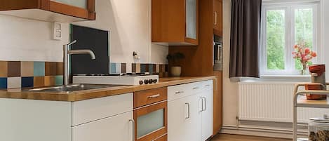 Una cocina moderna con armarios de madera, horno empotrado y un amplio ventanal con cortinas.