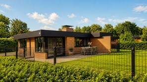 A modern building with a brick exterior, a covered patio area with outdoor seating, and a fenced garden. - Zenda's vakantiehuisje (Lanaken)