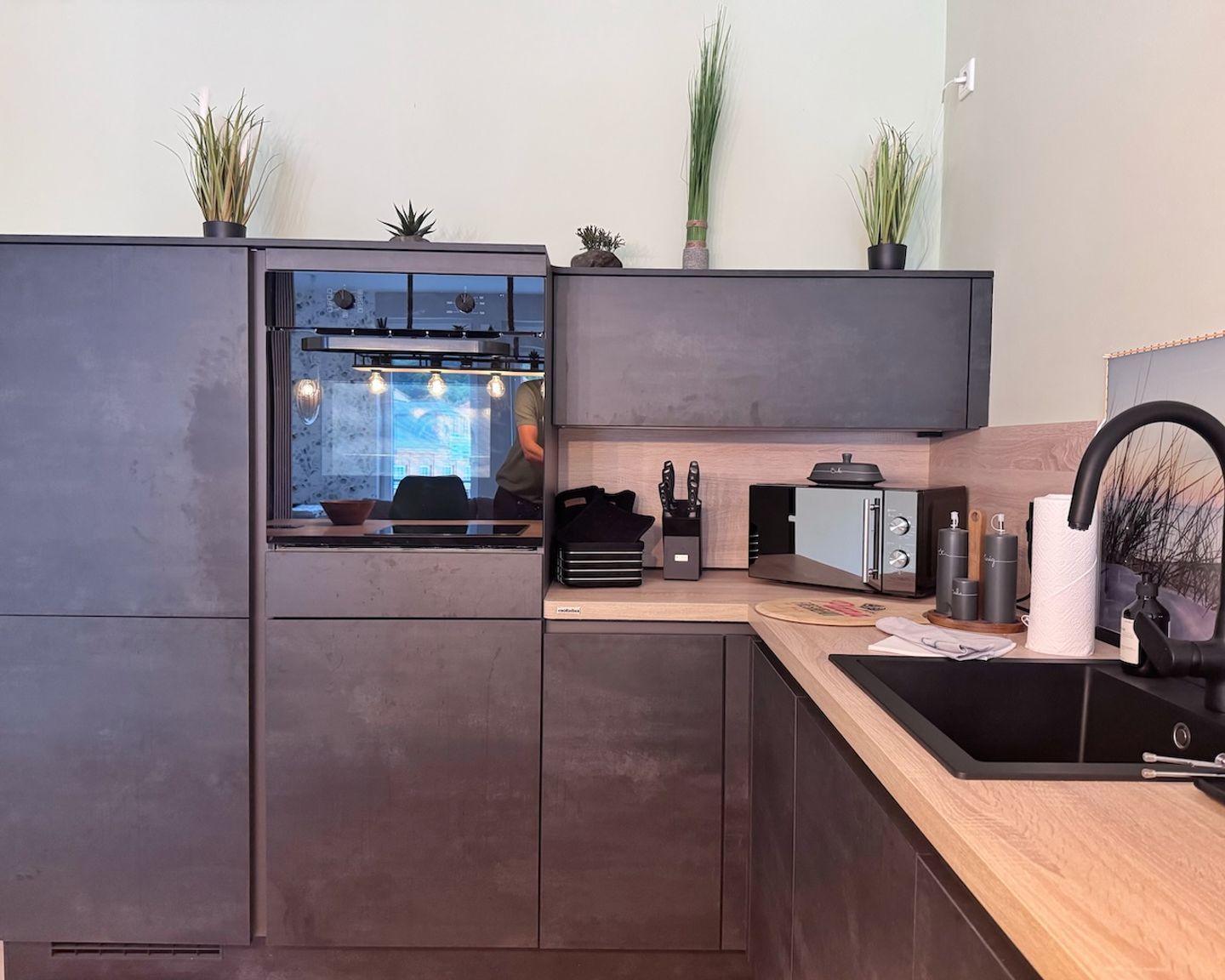 Eine moderne Küche mit eingebauten Geräten, einer Holz Arbeitsplatte und Zimmerpflanzen.