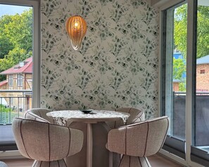 Ein Zimmer mit Tisch und Stühlen, einer gemusterten Tapete und einer Pendelleuchte.
