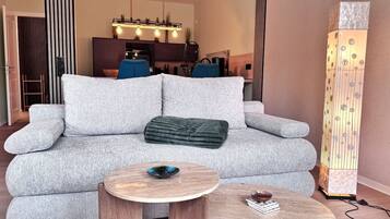 A modern living room with a grey sofa, two wooden side tables, and a decorative light fixture.