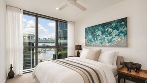 A bedroom with a large bed, a ceiling fan, a view of a river, and a painting on the wall. - Maison Quatre | Brisbane Skyline & River Escape (Brisbane City)