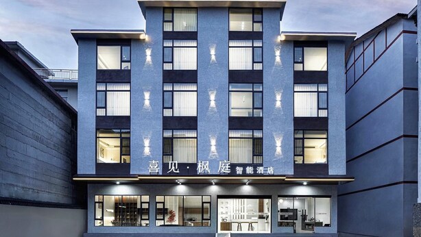 Un bâtiment moderne à la façade plate, doté de grandes fenêtres et d’une enseigne indiquant qu’il s’agit d’un hôtel.