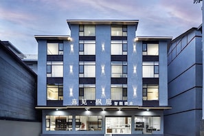 Un edificio moderno con fachada plana, ventanas amplias y un cartel que indica que es un hotel.
