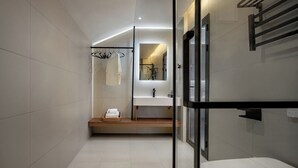 Une salle de bain moderne avec une douche à parois de verre, un lavabo blanc et un porte-serviettes.