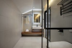 Ein modernes Badezimmer mit einer Glasdusche, einem weißen Waschbecken und einem Handtuchhalter.