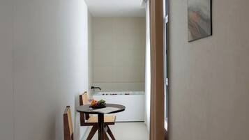 A modern room with a dining table, chairs, and a view of a bathroom with a bathtub.