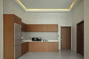 A modern kitchen with wooden cabinets, a built-in microwave, and a refrigerator. - JoyMaple Court Hotel (Wulingyuan Mark) (Zhangjiajie)