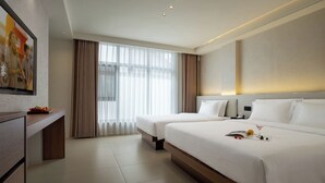 Une chambre d’hôtel avec deux lits, un téléviseur à écran plat, un coin repas et de grandes fenêtres.