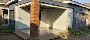 A residential building with a covered porch, a brick column, and a tiled entrance.