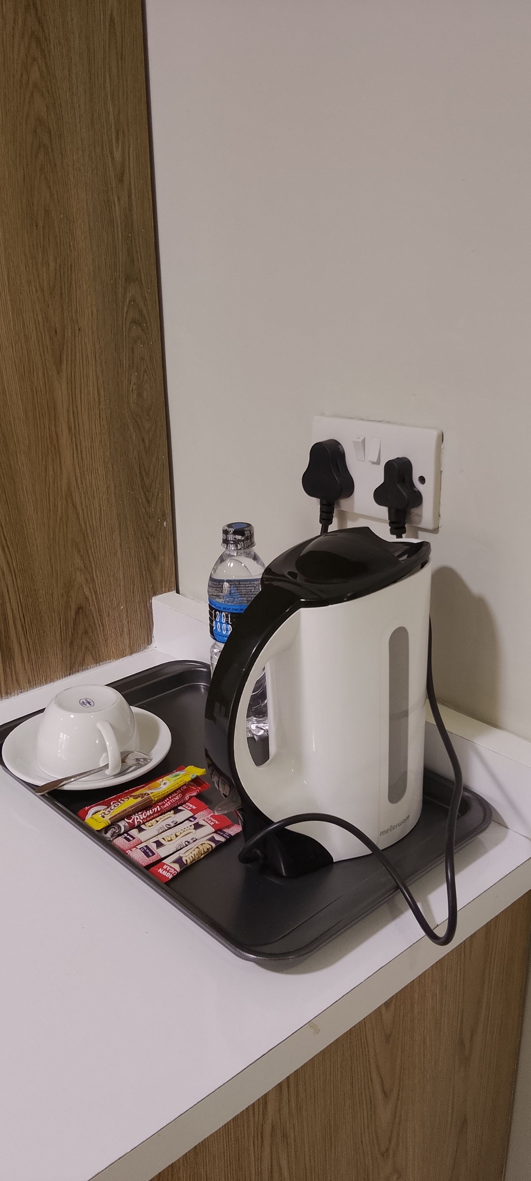 A kitchen counter with a coffee maker, a water bottle, and a packet of tea bags.
