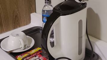 A kitchen counter with a coffee maker, a water bottle, and a packet of tea bags.