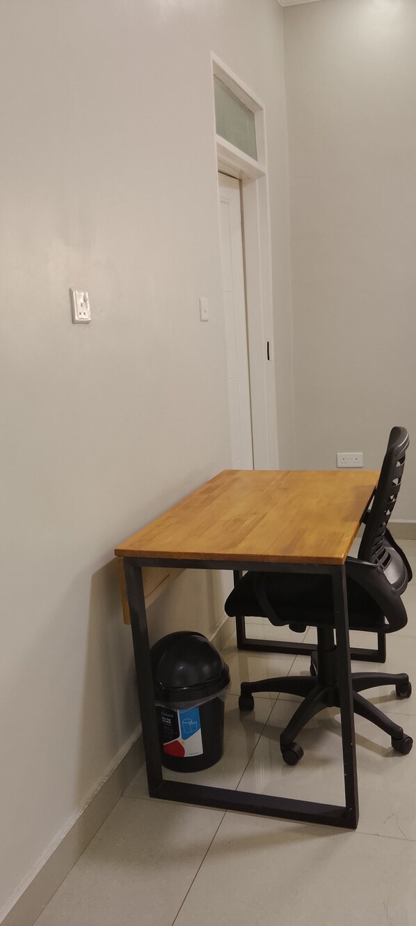 A conference room with a wooden table, black office chairs, and a black trash bin.