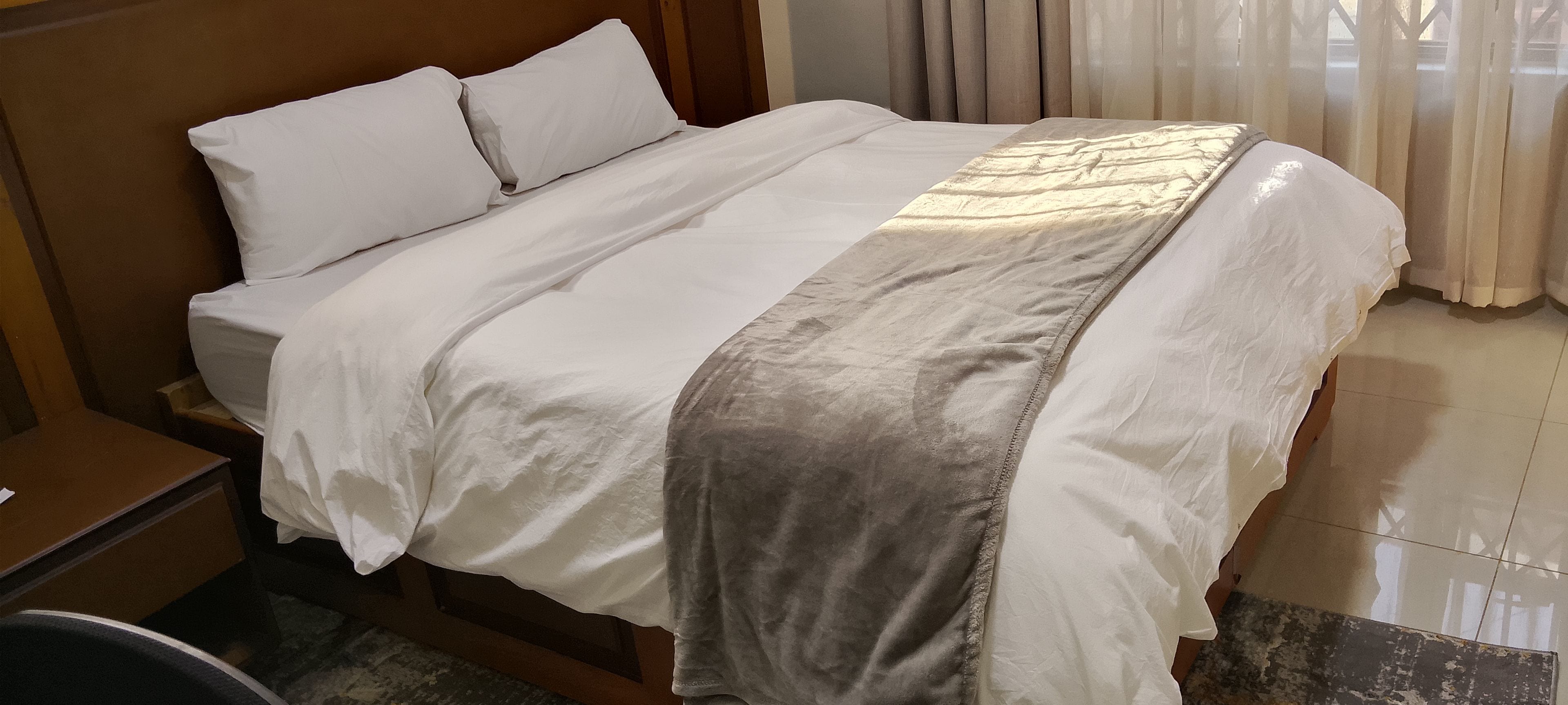 Ein Hotelzimmer mit Bett, Nachttisch und einem Vorhangfenster.
