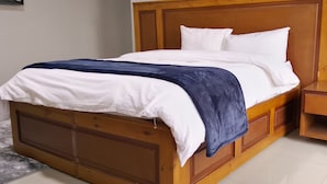 Ein Bett mit Holz-Kopfteil, weißer Bettwäsche und einer blauen Decke.