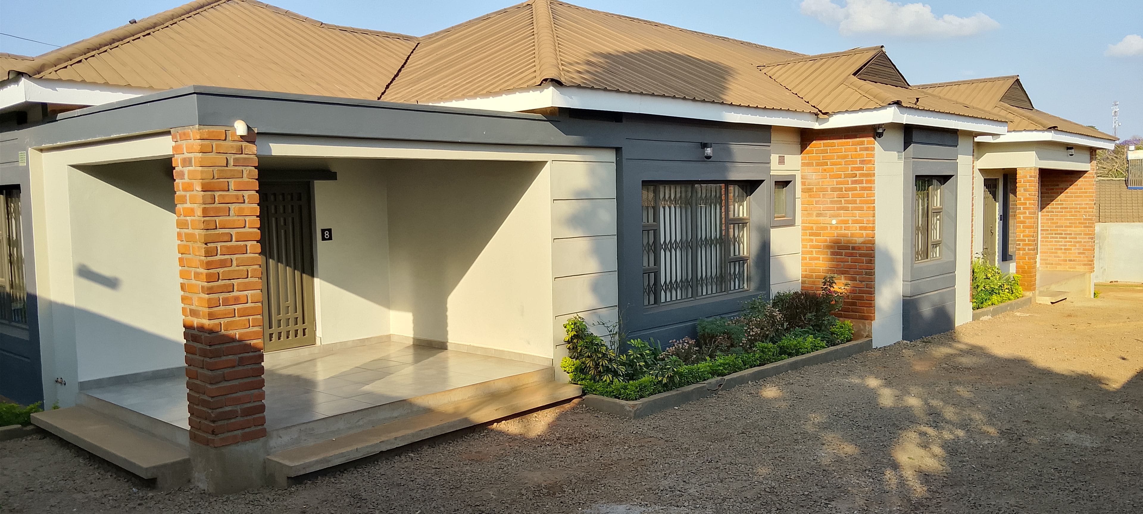 A residential building with a covered porch, a visible door, and a window with bars.