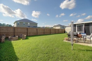 Ein Garten mit Holzpfeilung, Grill und Terrasse mit Stühlen.