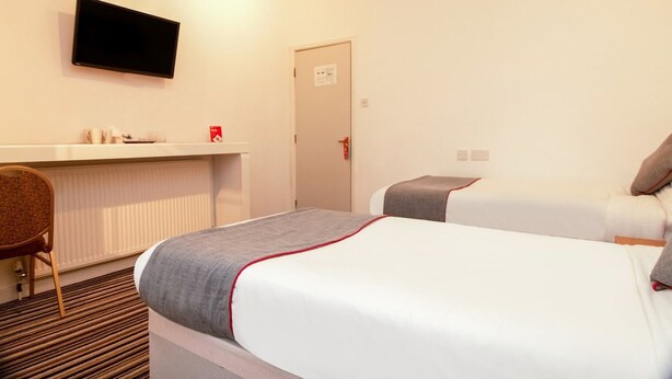 A hotel room with a bed, a desk, a chair, and a television on the wall. - Standard Double Room (Cardiff)
