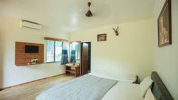 Un dormitorio con cama, televisor montado, equipo de aire acondicionado, ventilador de techo y decoración de cabeza de venado.