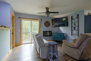Ein Wohnzimmer mit Deckenventilator, Flachbildfernseher, einer Uhr und einer blauen Kommode.