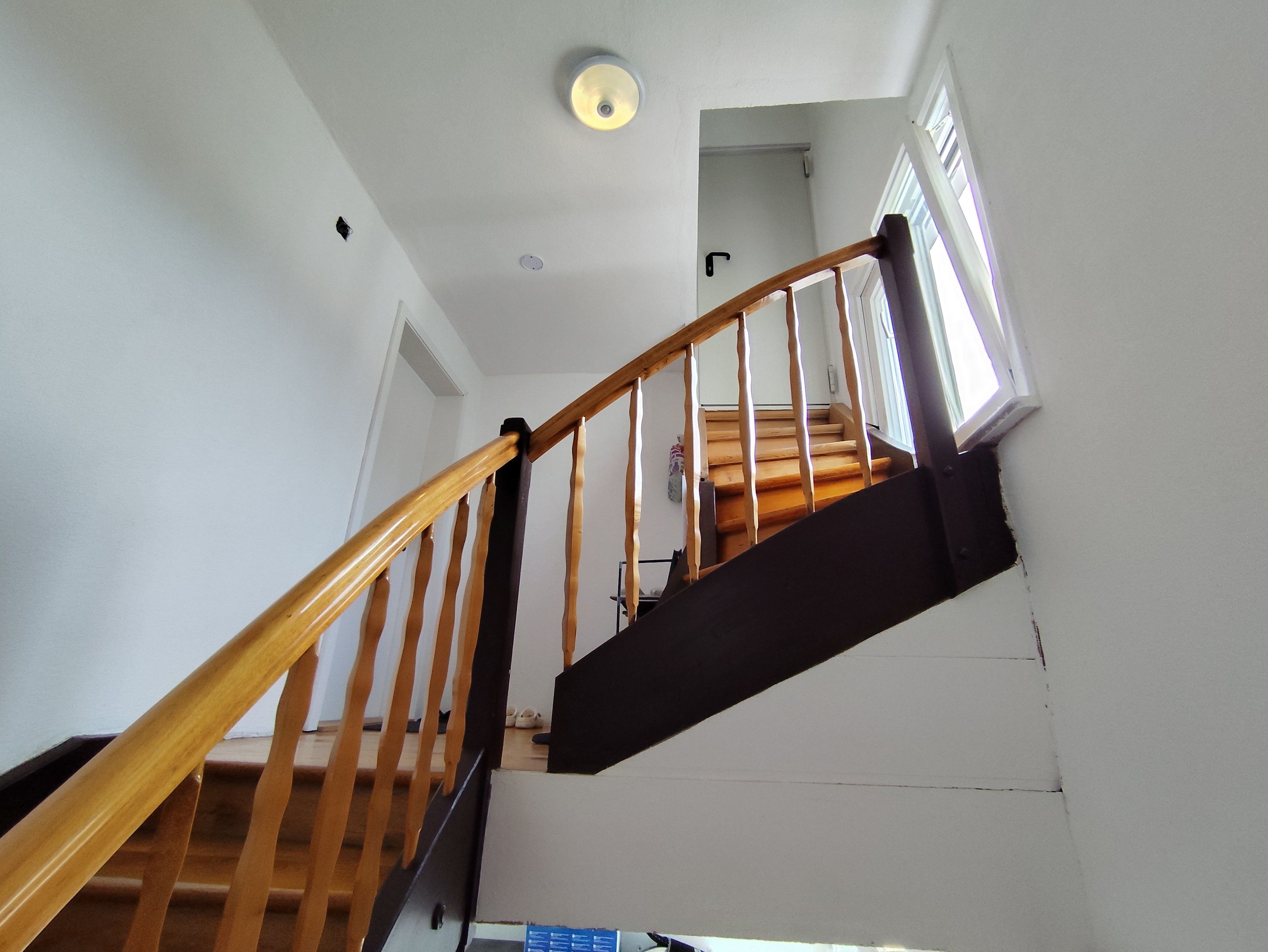 Eine hölzerne Treppe mit schwarzer Handlauf, die zu einer oberen Etage führt.