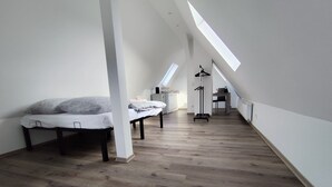 Habitación con techo inclinado y bajo, con dos camas, un radiador y un escritorio.