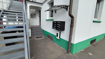 Een gebouw met een trap die naar een deur leidt, een aan de muur bevestigde brievenbus en een metalen leuning.