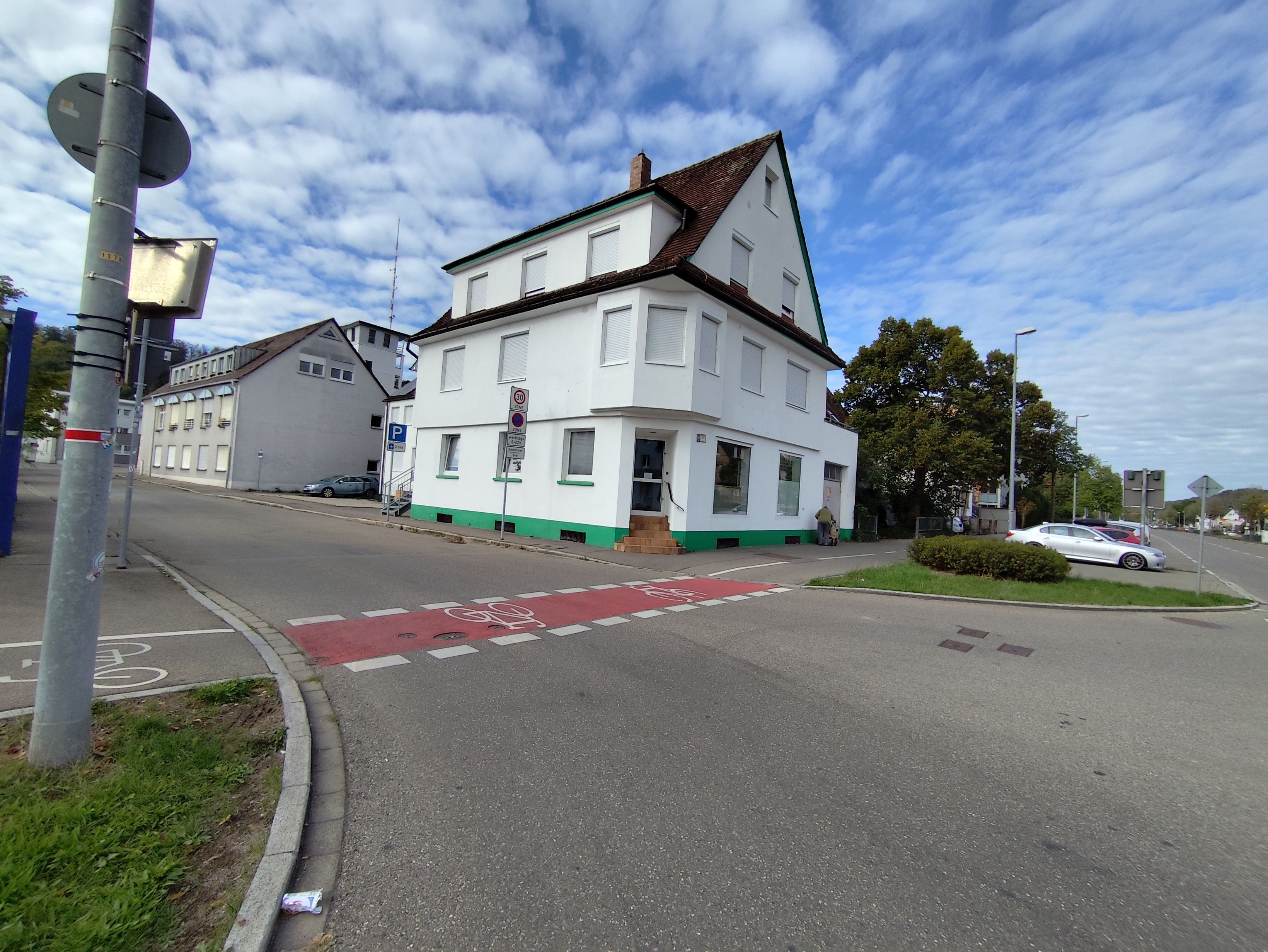 Een gebouw met een gevel in groen en wit, een duidelijke ingang en een heldere lucht.