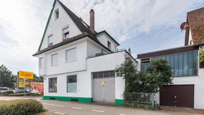 Un edificio blanco con detalles verdes, un garaje grande y una antena parabólica.