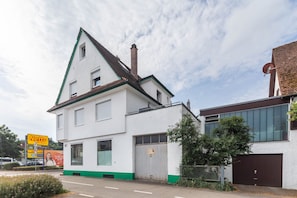 Um edifício branco com detalhes em verde, uma grande porta de garagem e uma antena parabólica.