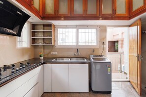 A kitchen with a gas stove, a sink, and a built-in oven. - Windsor by Redolive 15min Bagmane Tech Park 3bhk (Bengaluru)