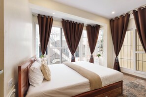 A bedroom with a large bed, a window with curtains, and a view of the outside. - Windsor by Redolive 15min Bagmane Tech Park 3bhk (Bengaluru)