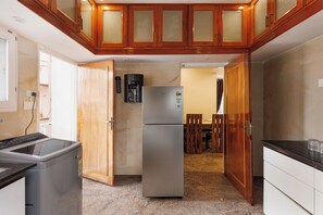 A compact kitchen with a refrigerator, a coffee maker, and a microwave. - Windsor by Redolive 15min Bagmane Tech Park 3bhk (Bengaluru)
