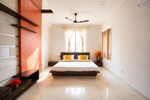 A modern bedroom with a large bed, a ceiling fan, and a window with curtains. - Mosaic by Redolive 4bhk Nr Gachibowli Nr Hitec (Hyderabad)