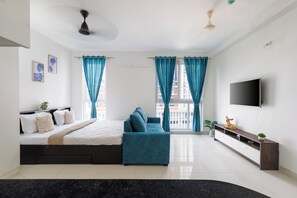 A modern bedroom with a bed, a sofa, a TV, and curtains. - Céleste Skies by Redolive Nr Manipal Whitefield (Bengaluru)