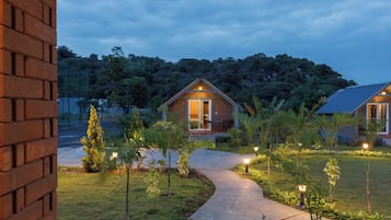 A house with a brick exterior, a paved pathway leading to the entrance, and a garden with various plants.