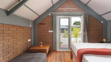 A bedroom with two beds, a small table, and a window with a view of the outside.