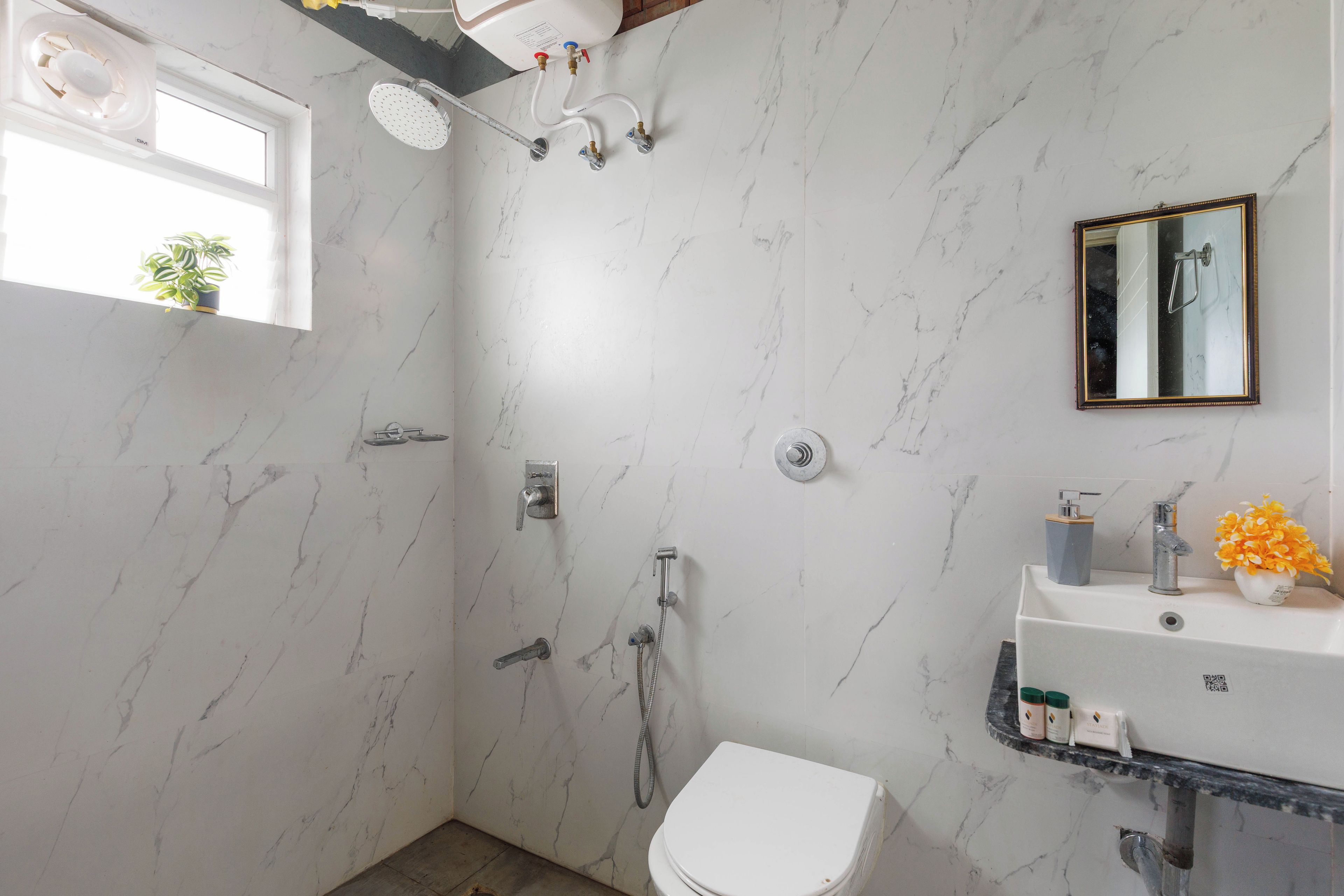 A bathroom with a shower, toilet, sink, and a mirror.