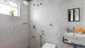 A bathroom with a shower, toilet, sink, and a mirror.