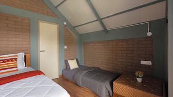 A room with a bed, a smaller bed, a wooden floor, a brick wall, and a ceiling with a skylight.
