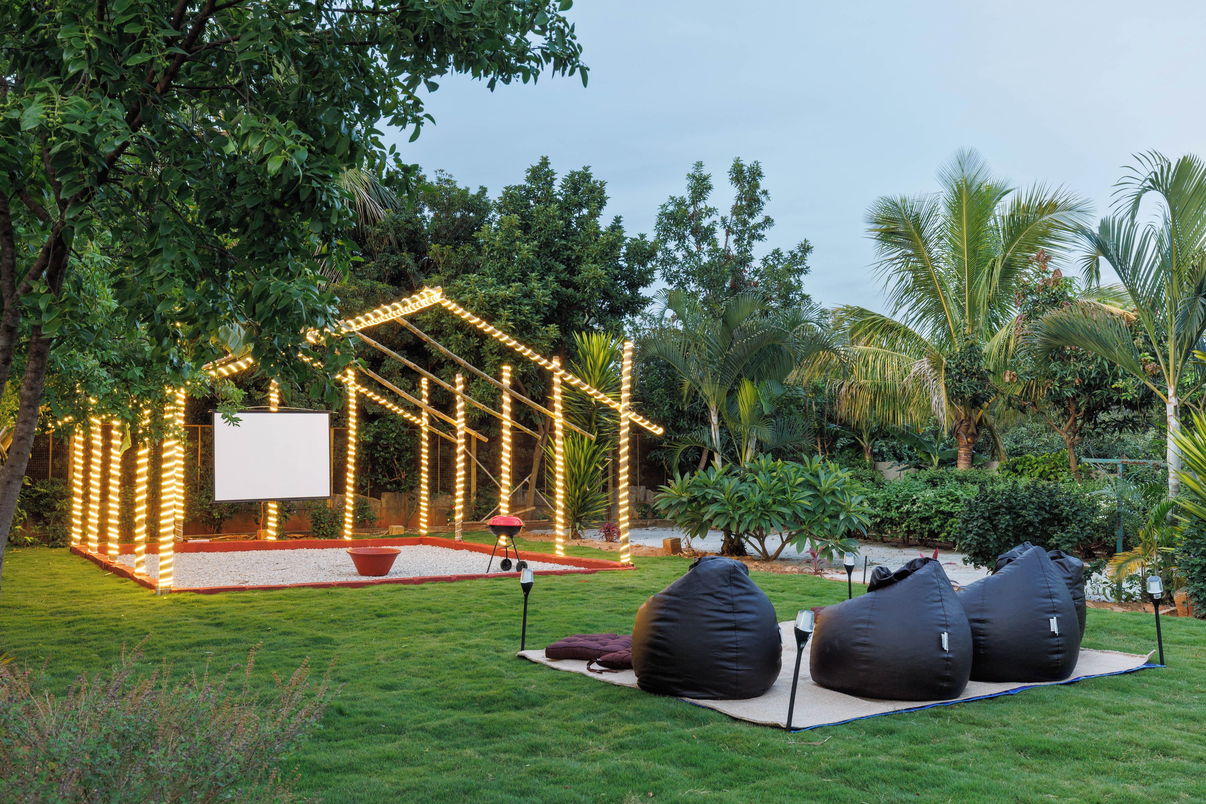 An outdoor seating area with bean bags, a barbecue grill, and string lights.