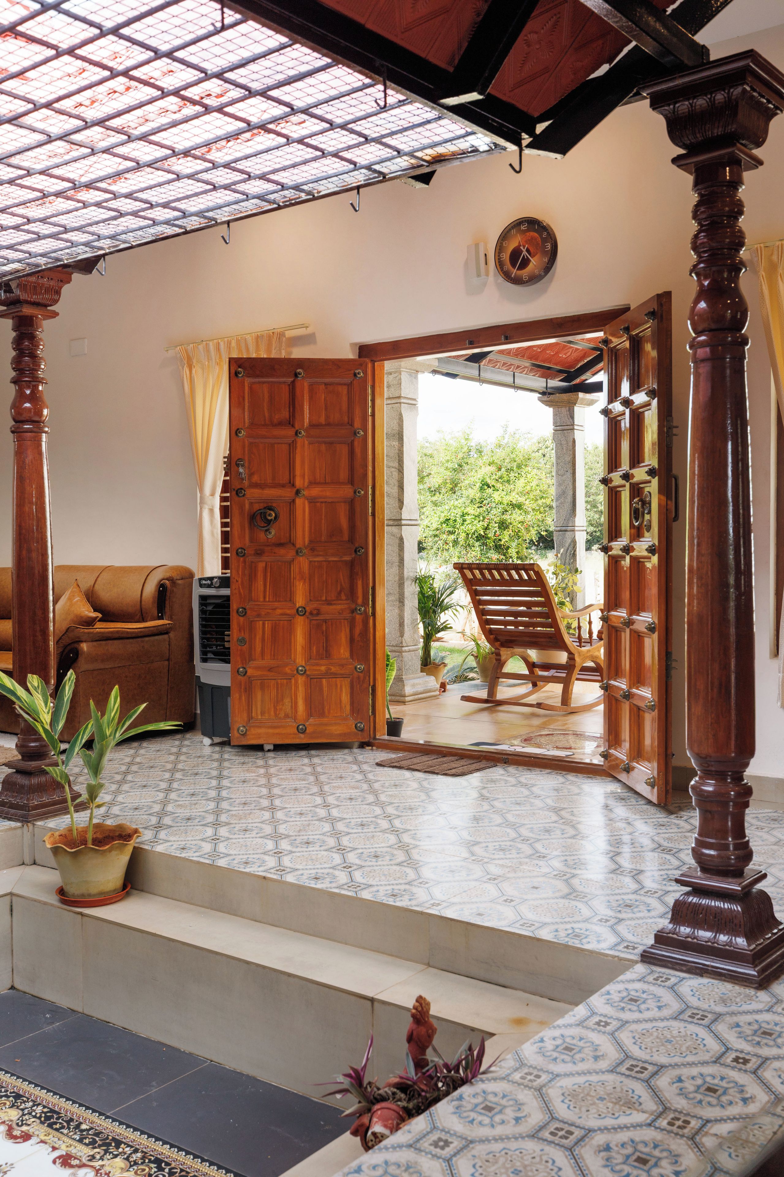 A spacious living area with a large wooden door, a sofa, and a rocking chair.