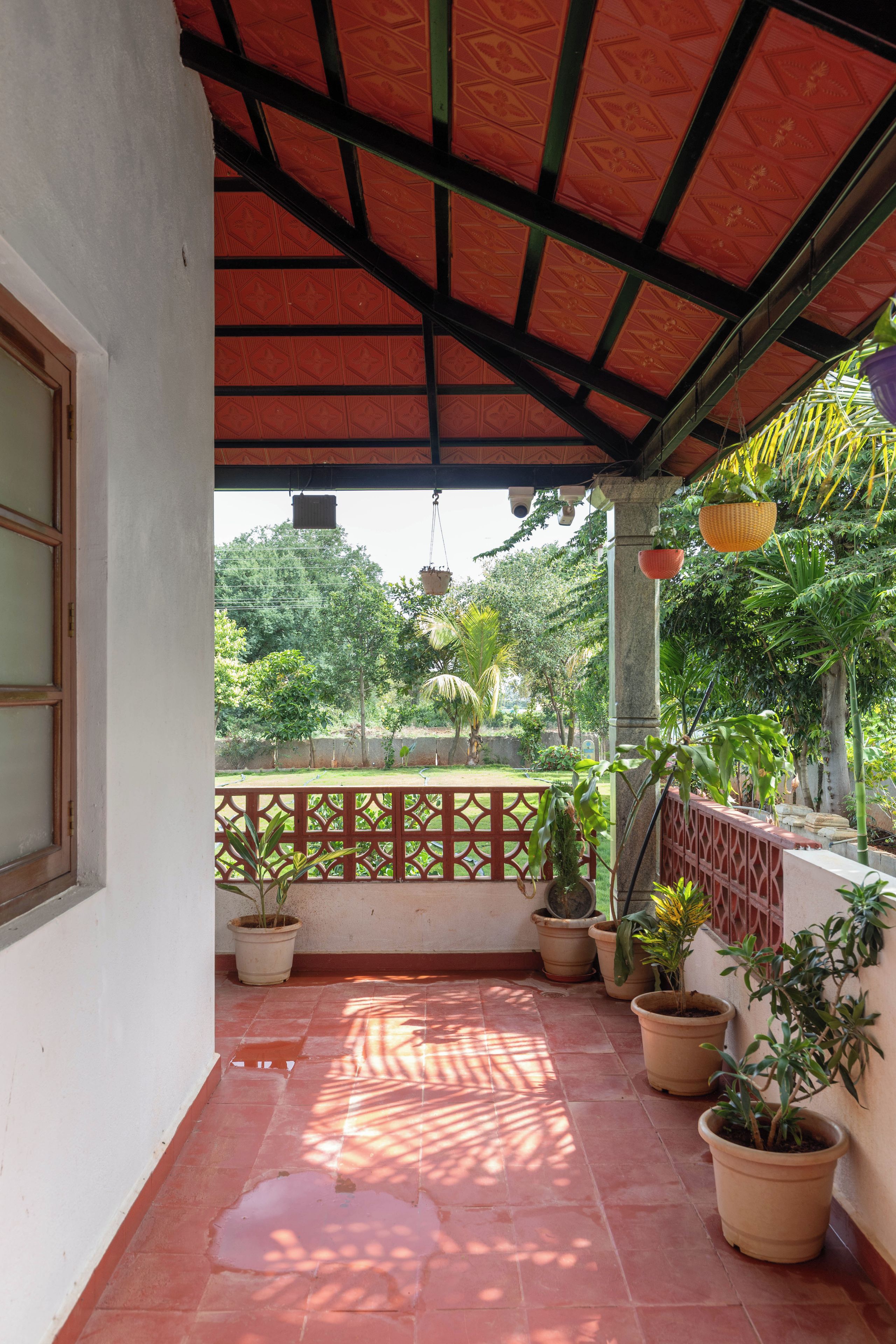 A covered balcony with potted plants and a view of greenery.