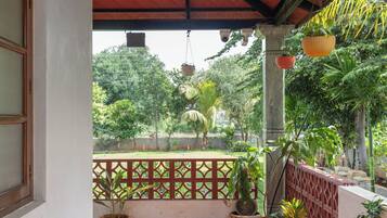 A covered balcony with potted plants and a view of greenery.