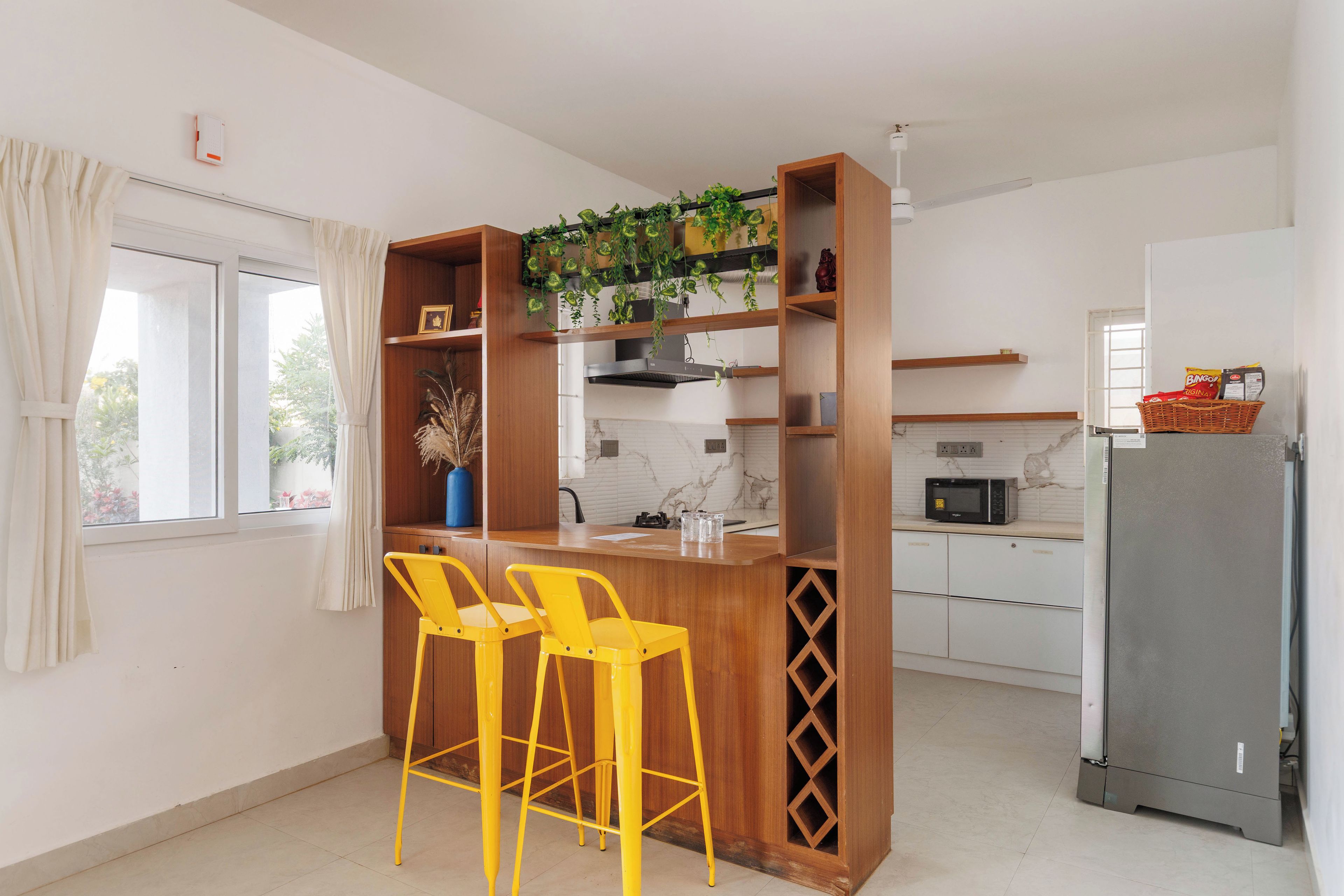 A kitchen with wooden bar stools, a microwave, and a refrigerator.